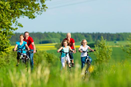 Family with three girls having a weekend excursion on their bikes on a summer day in beautiful landscape