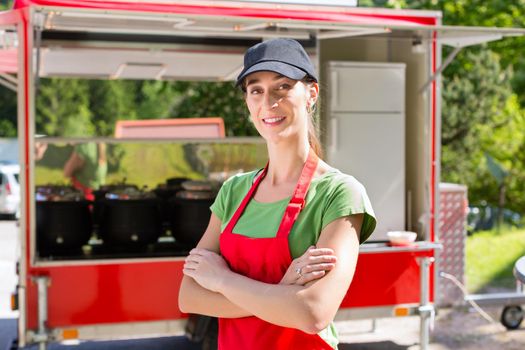 Female owner of a soup kitchen or a field kitchen standing in front of the food stall