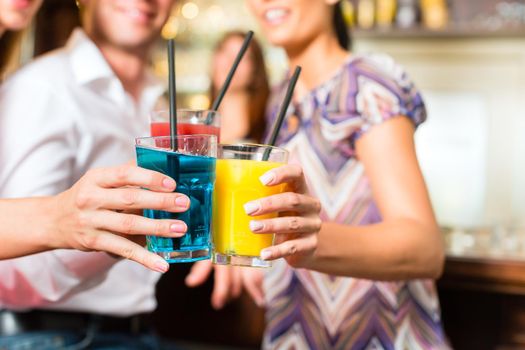 Young people drinking cocktails in bar having fun