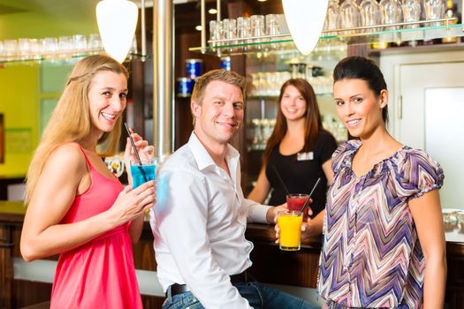 Young people drinking cocktails in bar having fun