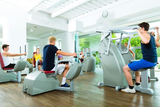 Group of men train on machine in a fitness club or gym