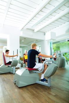 Group of men train on machine in a fitness club or gym