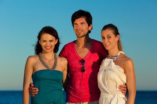 Man and two women enjoy the romantic sunset