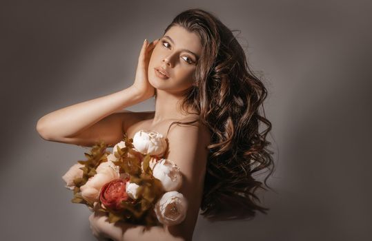 girl with a bouquet of artificial flowers on a gray background in the studio