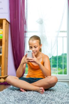 Family - child with cell or smartphone at home in the living room