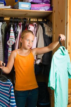 Family - child or teenager in front of her closet or wardrobe and looking for outfit