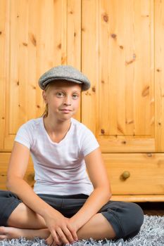 Family - child or teenager sitting with cap in room on the floor