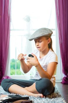 Family - child or teenager sitting with cap in room on the floor and is doing make-up