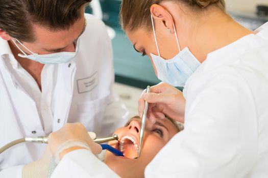 Female patient with dentist and assistant in a dental treatment, wearing masks and gloves