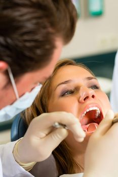 Female patient with dentist in a dental treatment, wearing masks and gloves