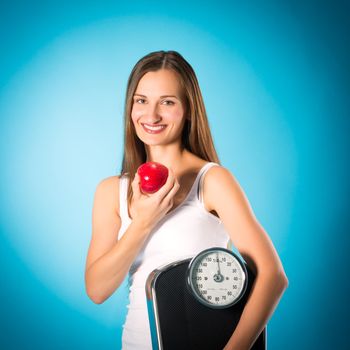 Diet and loosing weight, young woman with scale under her arm and apple