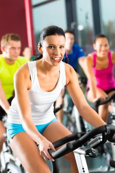 Young People - group of women and men - doing sport Spinning in the gym for fitness