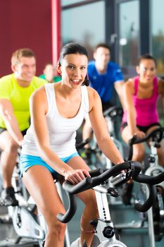 Young People - group of women and men - doing sport Spinning in the gym for fitness