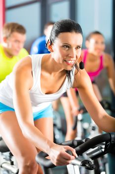 Young People - group of women and men - doing sport Spinning in the gym for fitness