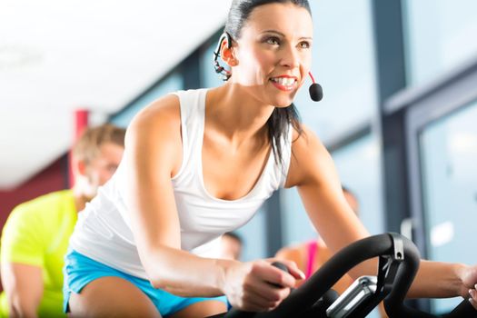 Young People - group of women and men - doing sport Spinning in the gym for fitness