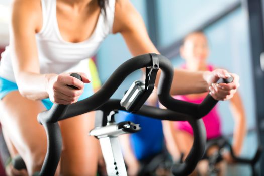 Young People - group of women and men - doing sport Spinning in the gym for fitness