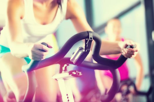 Young People - group of women and men - doing sport Spinning in the gym for fitness