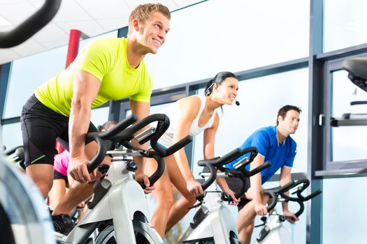 Young People - group of women and men - doing sport Spinning in the gym for fitness