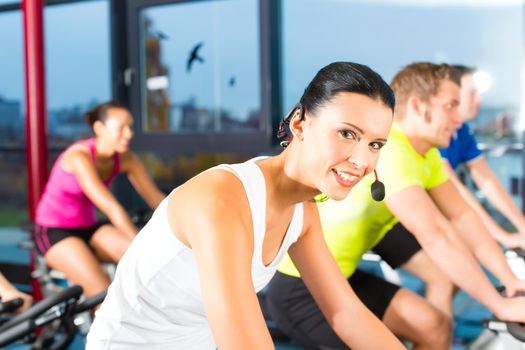 Young People - group of women and men - doing sport Spinning in the gym for fitness