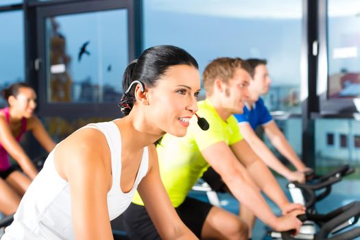 Young People - group of women and men - doing sport Spinning in the gym for fitness