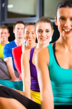 Group of young people stretching in gym for better fitness led by instructor