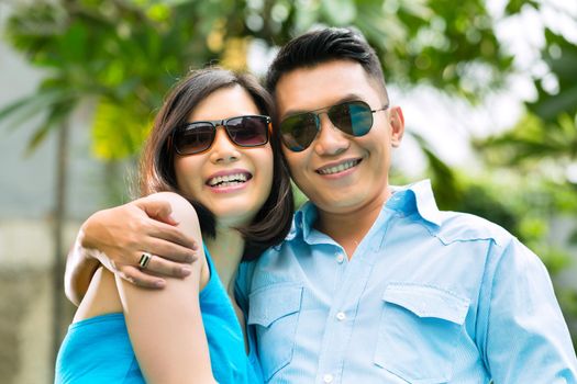 Indonesian couple in a tropical environment, he embraces his wife