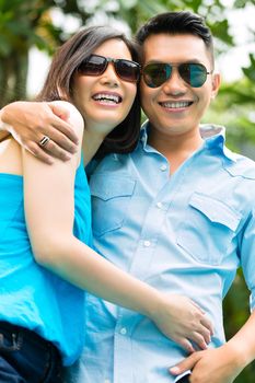 Indonesian couple in a tropical environment, he embraces his wife