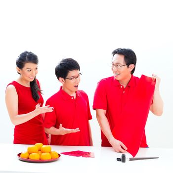 Friends family celebrate Chinese new year with traditional calligraphy, wearing red shirts