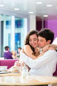 loving couple in a cafe or ice cream parlor spends leisure time together hugging and kissing