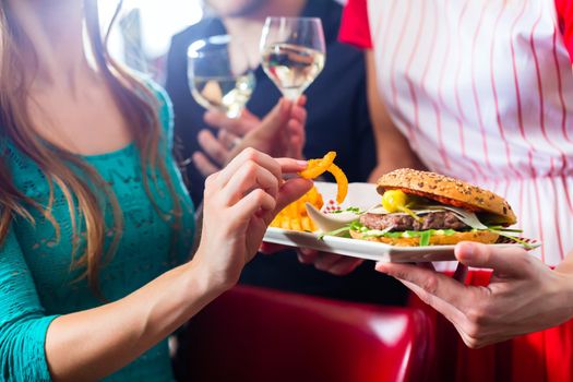 Friends or couple eating fast food in American fast food diner, the waitress serving the food and wine