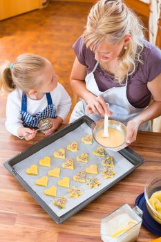 Baking with the family - Mother and daughter coat self made cookies with a brush