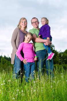 Mother, father and kids or daughter and friend standing outdoor on grass meadow