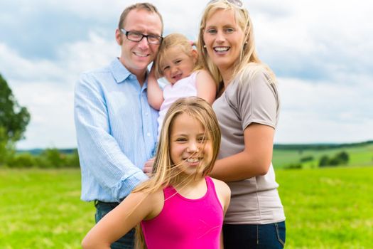 Happy Family with little girls or daughters in a meadow in summer