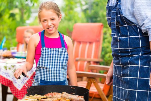 Father and daughter making barbecue in the garden in summer with sausages and meat