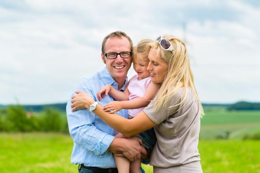 Happy Family with little girl or daughter in a meadow in summer