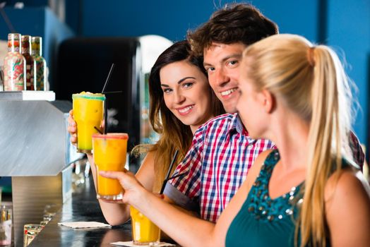 Young people in club or bar drinking cocktails and having fun