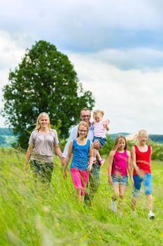 Happy Family with girls or daughters walking in a meadow in summer