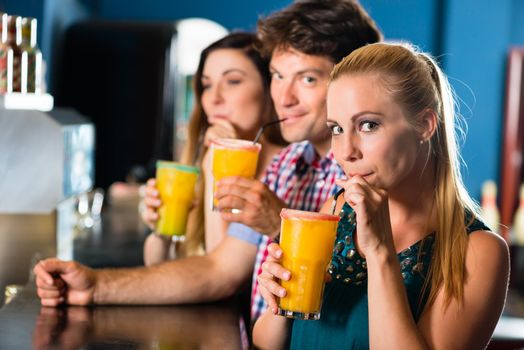 Young people in club or bar drinking cocktails and having fun