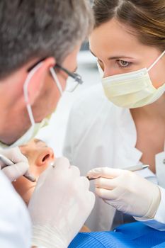 Female patient with dentist and assistant in a dental treatment, wearing masks and gloves