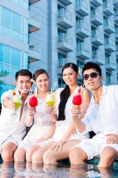 Two young and handsome Asian Chinese couples or friends drinking cocktails in a luxurious and fancy hotel pool bar