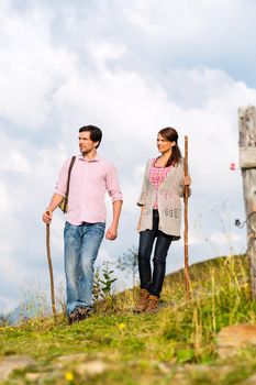 couple of man and woman hiking on mountain summit or alpine grassland in the Bavarian Alps, enjoys the panorama in the leisure time or in vacation