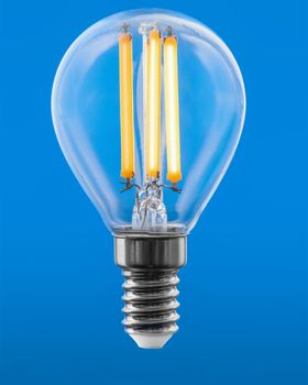 Energy efficient led filament Light Bulb Glowing isolated on blue background. Green Energy Concept