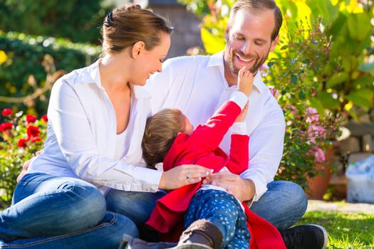 Family with mother, father and daughter together in the garden meadow