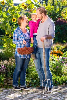 Family with mother, father and daughter gardening in garden