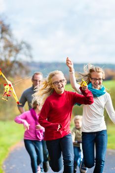 Family take walk in autumn forest flying kite