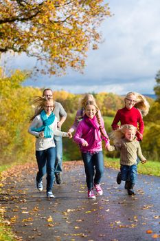 Girls running ahead at family walk through the park in fall or autumn