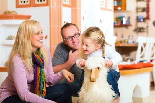 Parents and daughter rocking and playing with rocker horse in living room