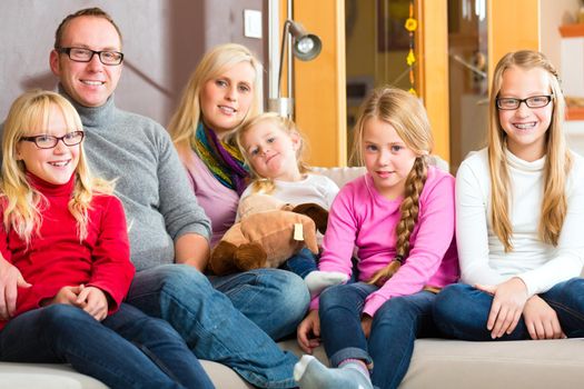 Family sitting together with mother, father and children comfortable on sofa