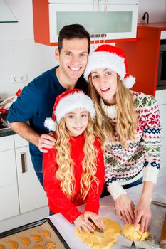 Mother and daughter baking Christmas cookies at home in domestic kitchen