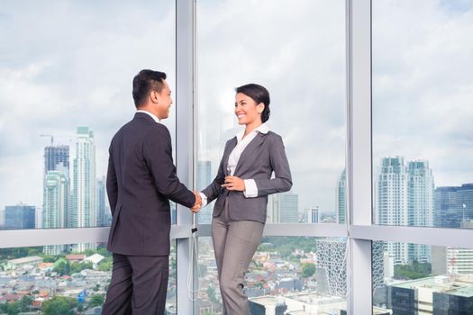 business people handshake to seal deal in front of city skyline